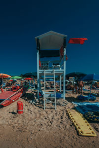 Lifeguard hut on beach against clear blue sky