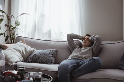 Young woman having headache sitting on sofa at home