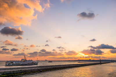 Ferry boat sailing in sea against sky during sunset