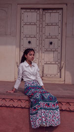 Portrait of smiling woman standing against door