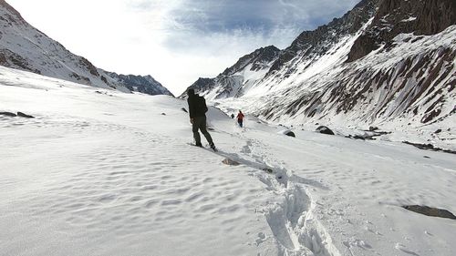 People on snowcapped mountain against sky