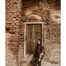 Portrait of woman standing against brick wall