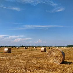 Hay bales on field against sky