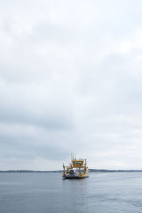 Yellow car ferry in sea against sky