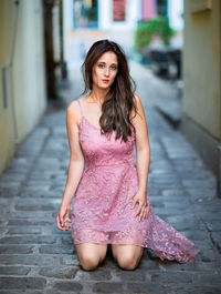 Portrait of beautiful young woman kneeling on footpath