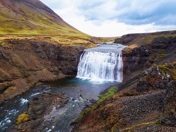 Scenic view of waterfall against sky