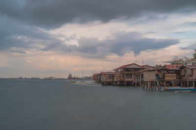 Scenic view of sea and buildings against sky at sunset