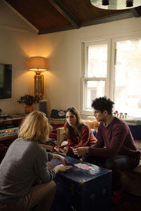 Friends playing with cards while sitting in living room at home