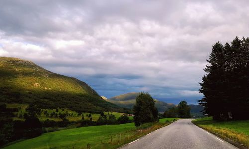 Road amidst green landscape against sky