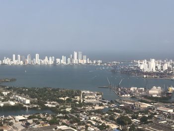 Aerial view of city by sea against sky