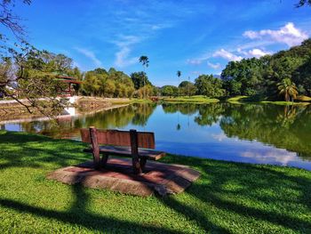 Empty bench by lake against sky