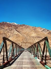 Footbridge against clear blue sky