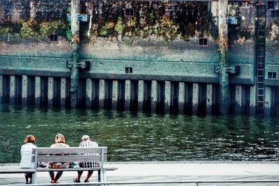 People sitting on bench by river