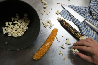 Cropped hand of boy holding popcorn in kitchen