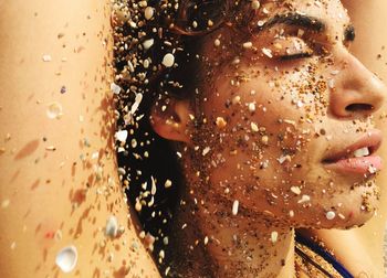 Close-up of woman face covered with seashells and sand