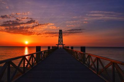 Pier over sea against sky during sunset