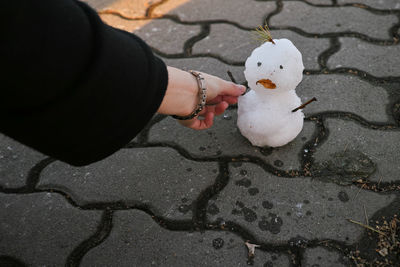 High angle view of hand holding snowman on footpath