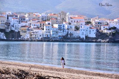 People standing on town by sea against city