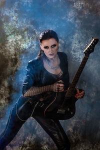 Portrait of young woman playing guitar