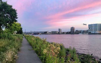 River amidst buildings against sky during sunset