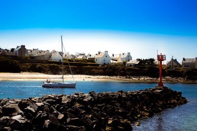 Sailboats moored on sea against buildings