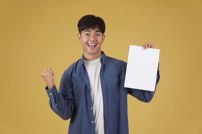 Portrait of a smiling young man against yellow background