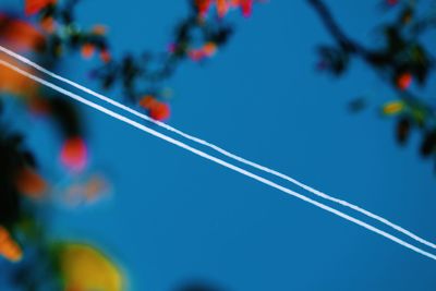Low angle view of vapor trails against clear blue sky