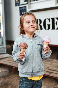 Happy smiling little girl holding two ice cream standing in front of food truck