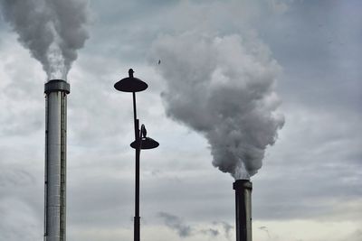 Low angle view of smoke emitting from chimney against sky