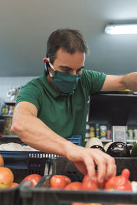 A fruit seller with a mask taking fruit from a box