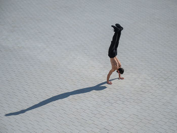 Full length of woman jumping on sand at beach