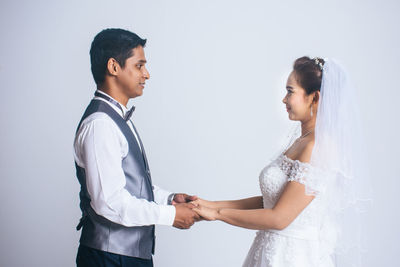 Side view of young couple standing against white background