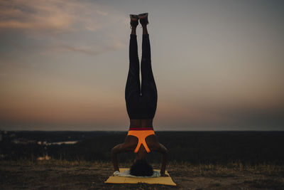 Sportswoman practicing yoga during sunset
