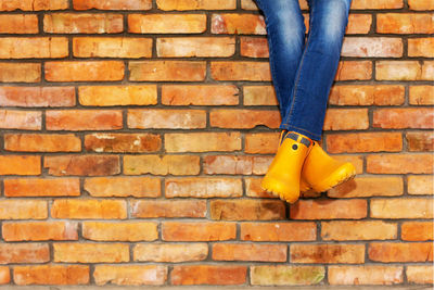 Low section of woman on brick wall