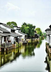Canal surrounded by houses against sky