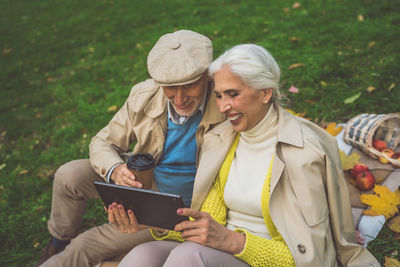 Woman holding mobile phone while sitting on laptop