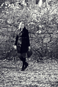 Full length portrait of young woman walking in forest