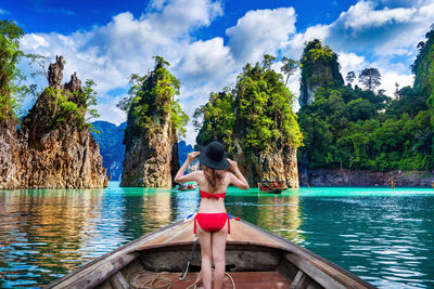 Rear view of woman with arms raised against sky