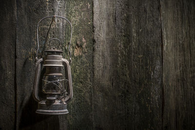 Close-up of old lantern on table against wall