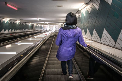 Rear view of woman standing on escalator