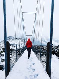 Rear view full length of woman walking on footbridge during winter