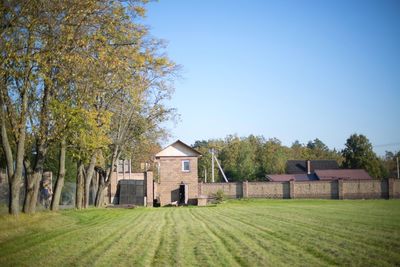 Houses by trees on field against clear sky