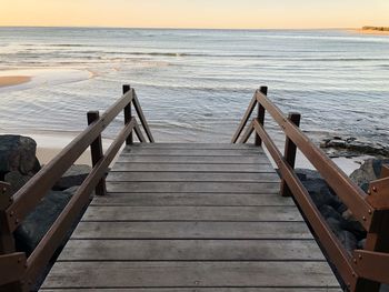 Pier over sea against sky during sunset