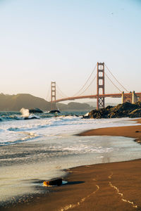 Suspension bridge over sea against clear sky