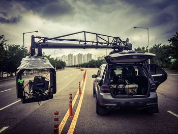 Cars on road against cloudy sky