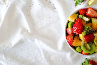 Top view of bowl of healthy fresh fruit salad on white napkin