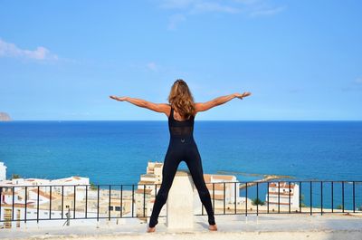 Rear view of woman exercising against sea