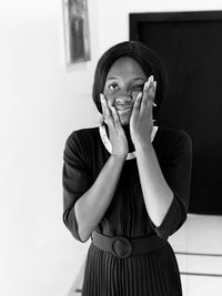 Portrait of smiling young woman standing against wall