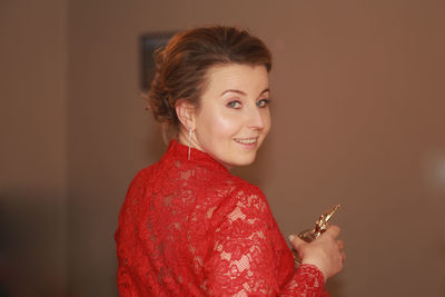 Portrait of smiling young woman against red background