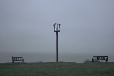 Lifeguard tower on field against sky